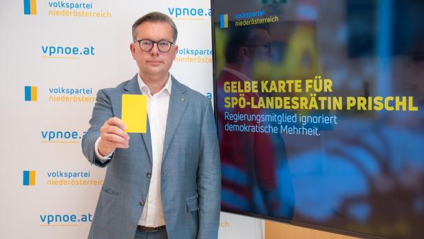 Mann im Anzug hält eine gelbe Karte; daneben steht auf einem Monitor: „Gelbe Karte für SPÖ-Landesrätin Prischl“.