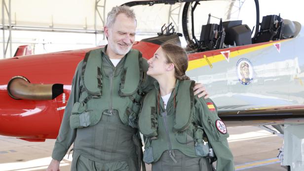 König Felipe VI. von Spanien steht in Fliegerkombi neben seiner Tochter Prinzessin Leonor vor einem Trainingsflugzeug.