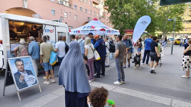 Menschen stehen vor einem Imbisswagen bei einer Wahlkampfveranstaltung der FPÖ mit Dominik Nepp in Wien.