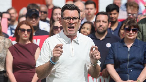 Andy Burnham spricht vor einer Menschenmenge in ein Mikrofon.