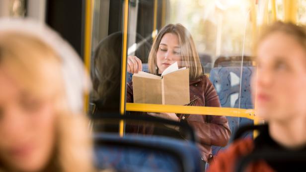 girl reading book in bus