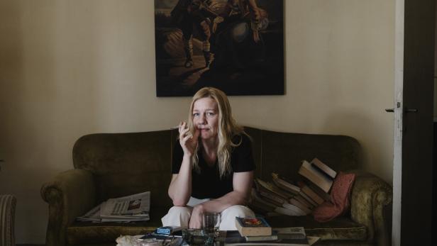 Sandra Hüller als Ingeborg Bachmann, rauchend auf einem Sofa.
