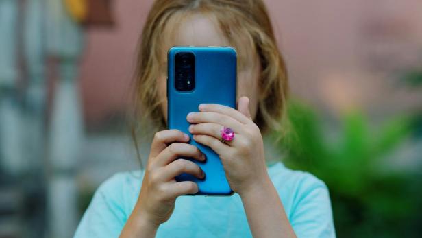 Mädchen hält Handy vors Gesicht