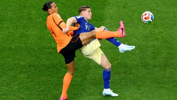 Virgil van Dijk im orangefarbenen Trikot kämpft auf dem Rasen um den Ball gegen einen Gegenspieler in Blau.