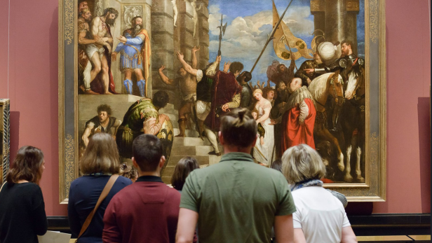 Besucher im Kunsthistorischen Museum betrachten ein großes Historiengemälde mit Soldaten, Reitern und Jesus.