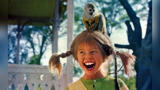 Pippi Langstrumpf lacht fröhlich mit ihrem Totenkopfäffchen Herr Nilsson auf dem Kopf.