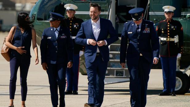 J.D. Vance geht in Begleitung von Militärangehörigen vor einem Hubschrauber über ein Rollfeld.
