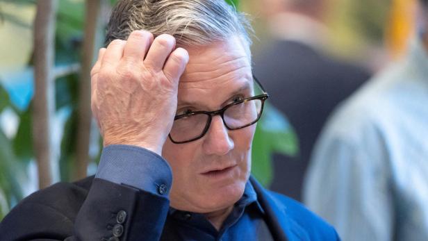 Keir Starmer trägt eine Brille und fährt sich nachdenklich mit der Hand durch das graue Haar.