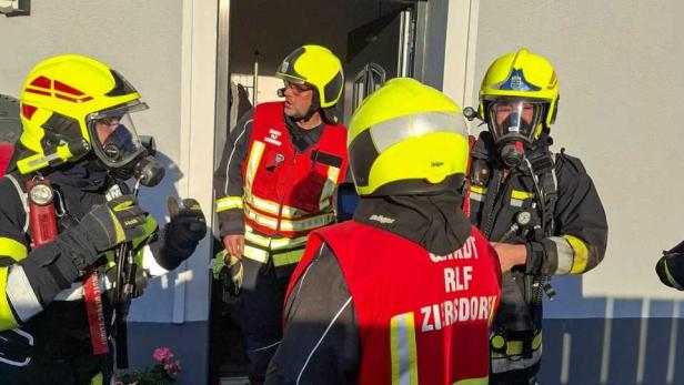 Feuerwehrleute in Atemschutz vor einem Haus nach dem Brand.