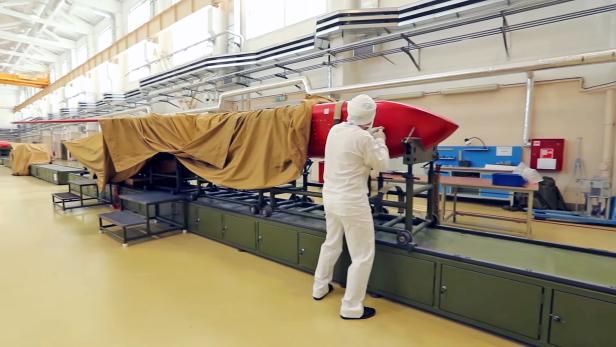 Eine Rakete in einer Produktionshalle wird von einer Person überprüft.