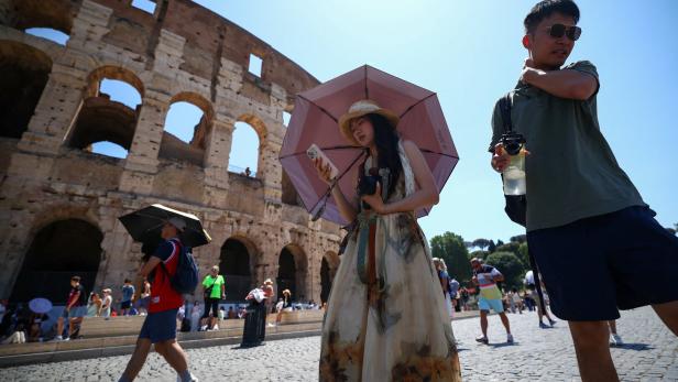 Near the Temple of Claudiuss underground spaces, tourists brave the heat at Romes Colosseum