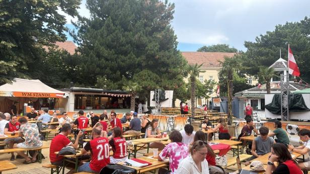 Menschen sitzen auf Bänken beim Public Viewing Ort 