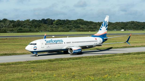 Ein großes "SunExpress"-Passagierflugzeug sitzt auf der Landebahn eines Flughafens