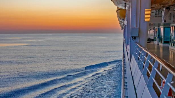 Blick vom Kreuzfahrtschiff auf das ruhige Meer bei Sonnenuntergang.