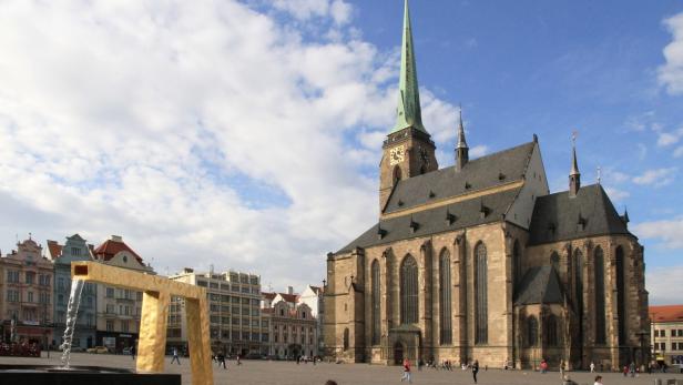 Der Platz der Republik in Pilsen mit der St.-Bartholomäus-Kathedrale und einem goldenen Brunnen.