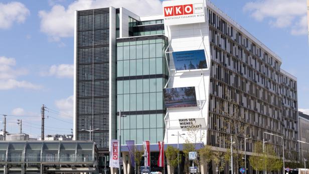 Das moderne Gebäude der WKO Wien mit Glasfassade und digitalen Anzeigetafeln steht unter blauem Himmel.
