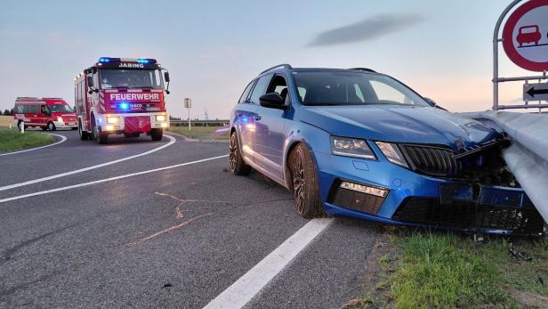 Blauer Kombi ist in die Leitplanke geprallt, Feuerwehrfahrzeuge sichern die Unfallstelle.