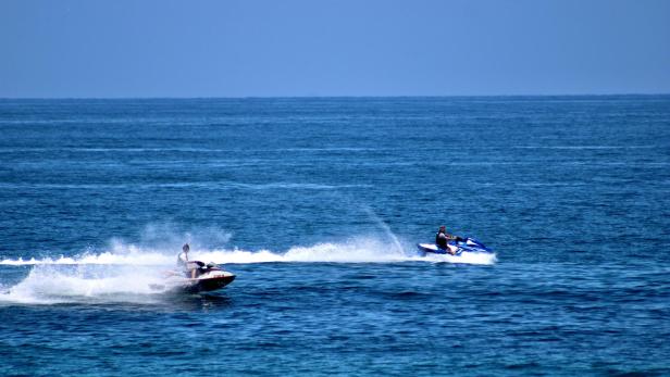 Zwei Jetskis rasen nebeneinander über das Wasser