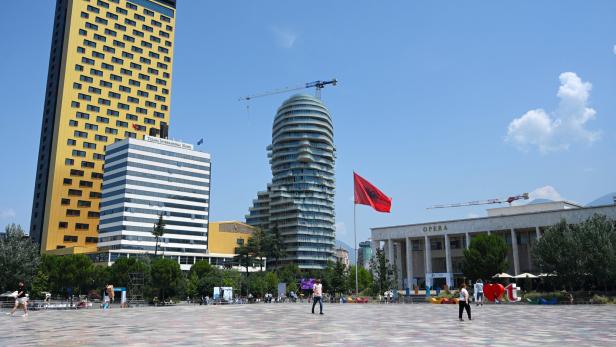 Der Skanderbeg-Platz in Tirana mit dem InterContinental Hotel, dem markanten Eye of Tirana Hochhaus und der albanischen Flagge vor der Oper.