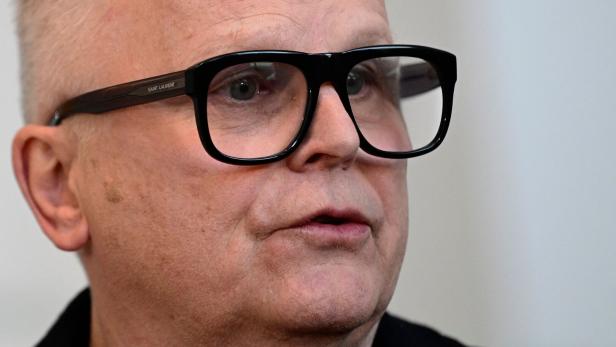 Nahaufnahme von Herbert Grönemeyer mit heller Haut und kurz geschorenem Haar, der eine markante schwarze Brille von Saint Laurent trägt.