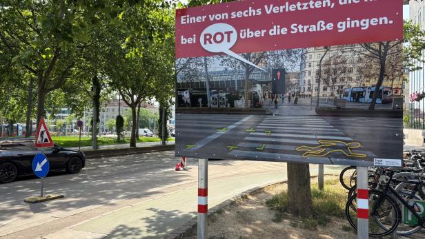 Ein Verkehrssicherheitsplakat der Stadt Wien warnt mit einer Grafik eines Zebrastreifens vor dem Überqueren der Straße bei Rot.