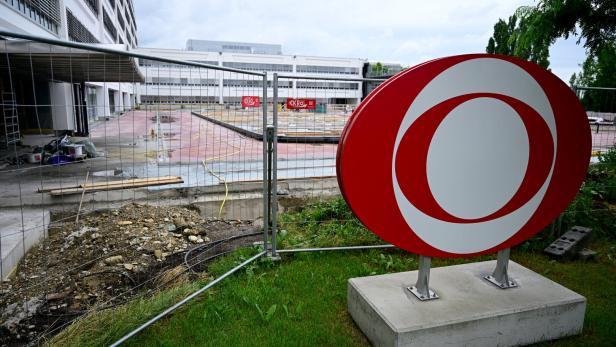 Auf der Baustelle am Küniglberg steht ein großes rotes rundes ORF.Schild vor einem abgesperrten Schulhof.