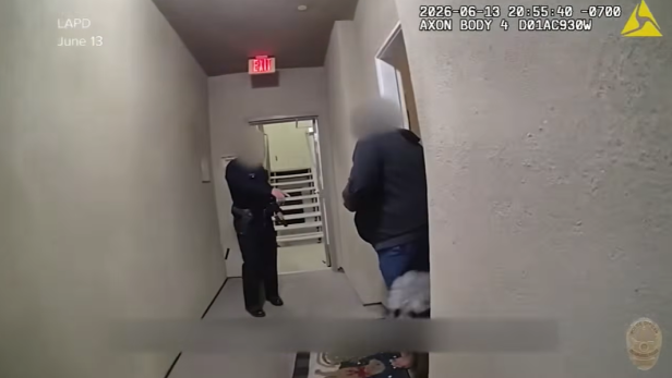 Bodycam zeigt Polizisten in einem engen Hausflur vor einer Wohnungstür.