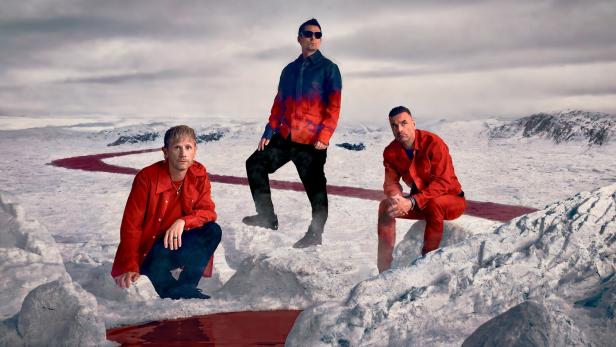 Die drei Bandmitglieder von Muse im Schnee.