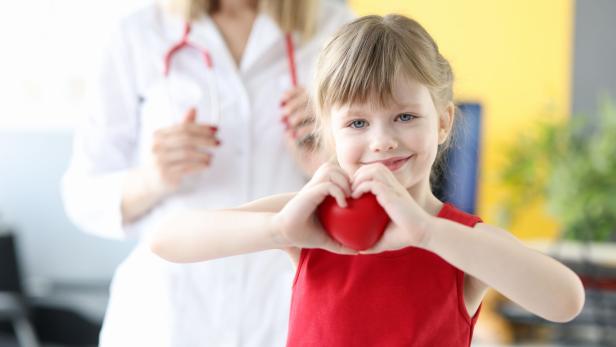 Little girl showing heart with hands in doctors office