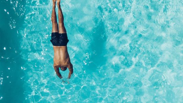 Mann springt kopfüber in einen Pool.