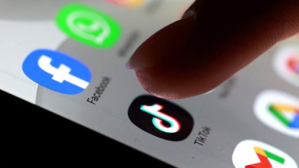 Finger tippt auf Smartphone-Startbildschirm mit App-Symbolen wie Facebook und TikTok.