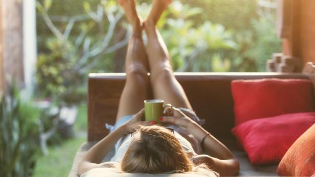 Girl drinking coffee / tea and enjoying the sunrise / sunset in garden.