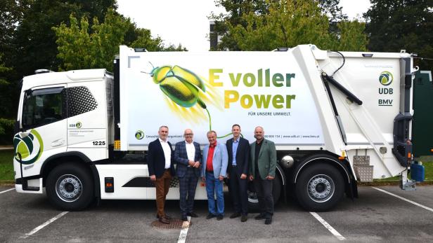 Fünf Männer stehen vor einem Müllwagen mit der Aufschrift „E voller Power“ und einem Käfermotiv.
