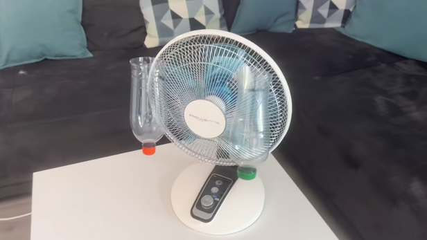 Ventilator mit zwei leeren Plastikflaschen, die vorne am Gitter befestigt wurden