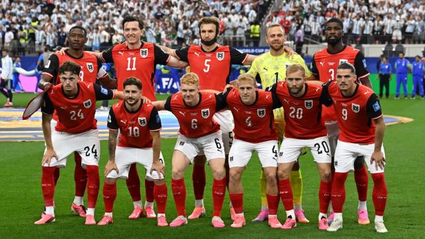 Österreichische Fußballmannschaft posiert vor dichtem Stadionpublikum vor dem Spiel.