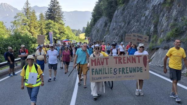 Demonstranten marschieren auf der Fernpassstraße bei Tirol mit Transparenten gegen das Fernpasspaket.