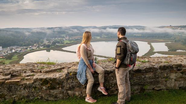 Zwei Personen stehen vor einer Steinmauer