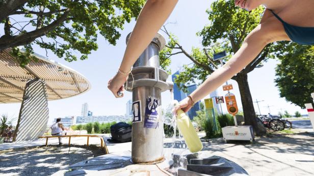 Wasserflasche wird an einem heißen Tag an einem Trinkbrunnen aufgefüllt.