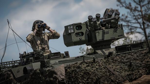 Soldat mit Feldstecher sitzt auf einem Panzer