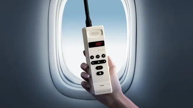 Hand hält ein Gerät mit Antenne vor einem Flugzeugfenster.