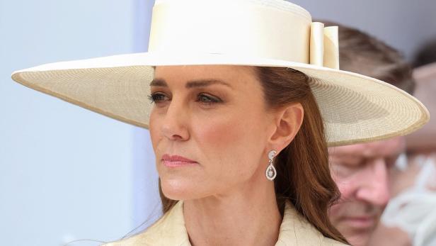 Prinzessin Kate trägt einen cremefarbenen Hut und passende Ohrringe.
