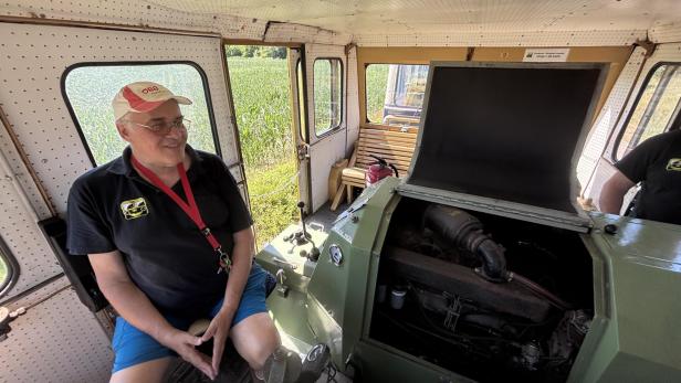 Mann sitzt in einem Zug mit einem historischen Motor.