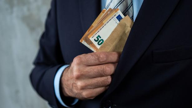 Man in Suit Concealing Cash in Envelope