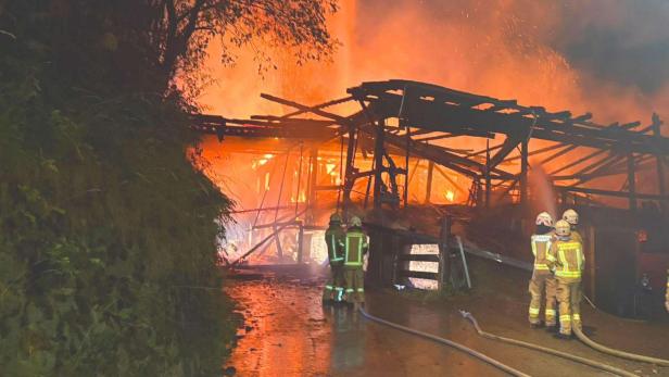 Feuerwehrkräfte löschen brennendes Bauernhofgebäude.