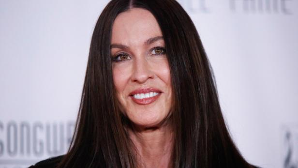 Alanis Morissette lächelt in die Kamera vor einem hellen Hintergrund.