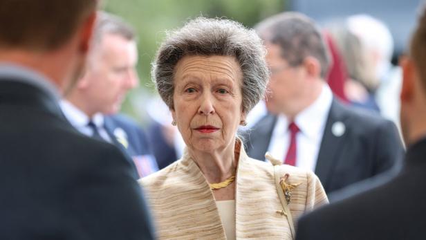 Prinzessin Anne trägt eine beige Jacke und blickt ernst in einer Menschenmenge umher.