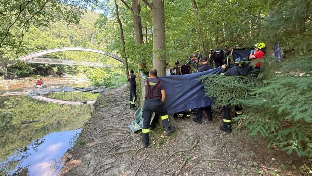 Feuerwehrleute schirmen eine Unfallstelle neben einem Fluß ab