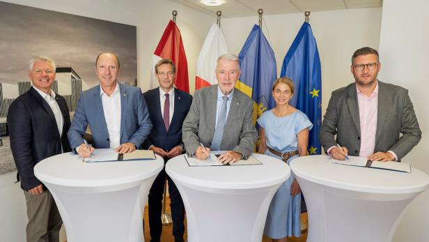 Sechs Personen stehen vor Fahnen