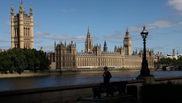 A man looks out over the River Thames opposite the Houses of Parliament and the Elizabeth Tower, commonly known as Big Ben, in London