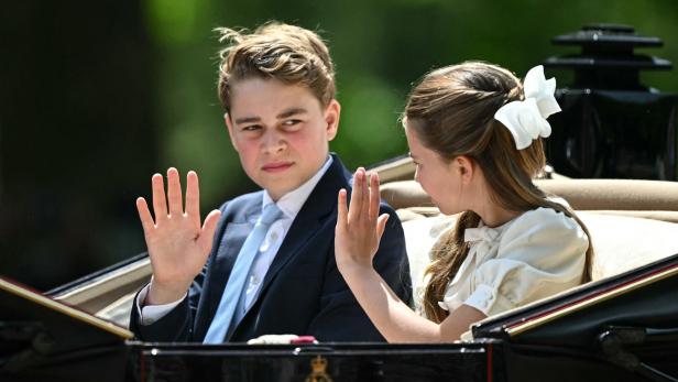 Prinz George und Prinzessin Charlotte winken in einer Kutsche sitzend der Menge zu.